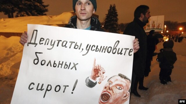 Un manifestante sujeta un cartel en el que se puede leer 'Legisladores, adoptad niños enfermos' durante una manifestación en contra de la ley que prohíbe adoptar niños a Estados Unidos, en San Petersburgo, Rusia.  