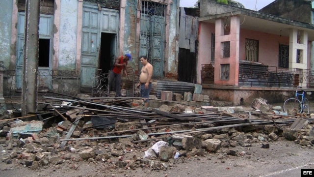 Dos hombres limpian escombros en una casa que ha sido parcialmente destruida por el paso del huracán "Sandy".