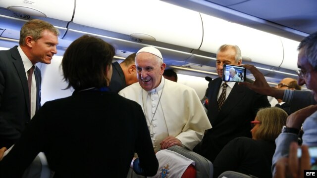 El papa Francisco saluda a periodistas a bordo del avión de Alitalia.