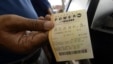 Un hombre muestra un boleto de lotería Powerball. 