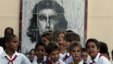 Unos estudiantes cubanos conversan junto a un mural con la imagen de Ernesto 