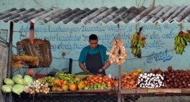 Un hombre vende frutas y verduras en un mercado agropecuario