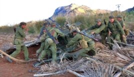 Soldados cubanos desenmascaran una pieza de artillería.