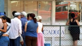 Varias personas hacen cola frente a una Casa de Cambio (CADECA).