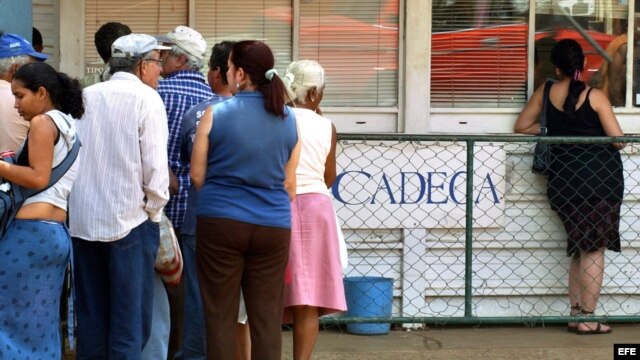 Varias personas hacen cola frente a una Casa de Cambio (CADECA).