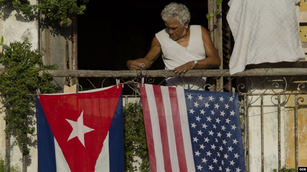 Un hombre coloca las banderas de EE.UU. y Cuba.