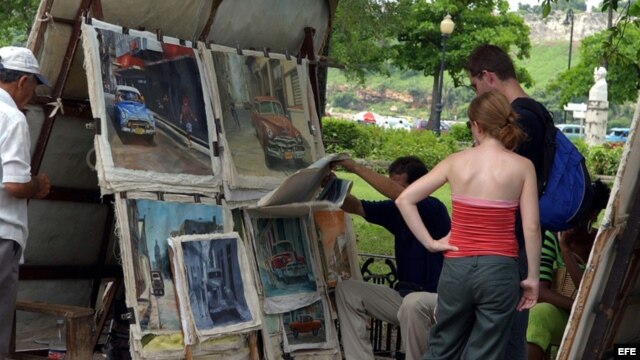 Turistas observan pinturas expuestas en una feria de artesanos de La Habana Vieja. 