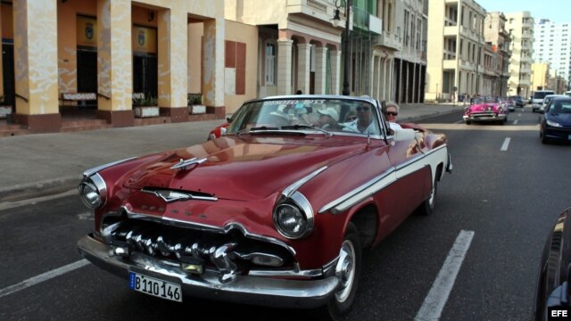 Turistas en un viejo auto descapotable, por el malecón de La Habana.