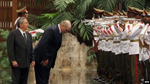 El presidente de Bielorrusia, Alexandr Lukashenko (c), y su homólogo cubano, Raúl Castro (i), pasan revista a las tropas durante una ceremonia oficial. 