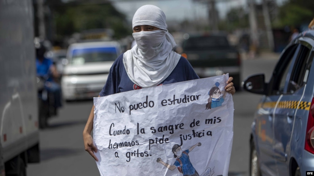 Una joven con la cara tapada y un cartel participa de un plantÃ³n contra el Gobierno de Nicaragua.