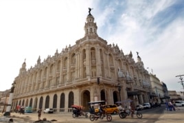 Varios bicitaxis pasan frente al gran Teatro de La Habana "Alicia Alonso".