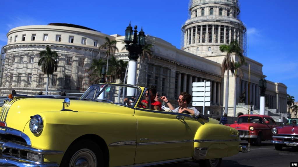 Dos turistas viajan en un viejo auto descapotable por una calle de La Habana Vieja. (Archivo)