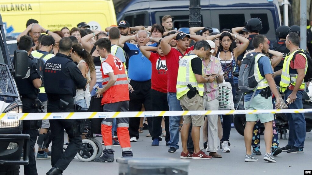 Un grupo de gente con los brazos en alto ante el despliegue policial en el lugar del atentado ocurrido hoy en las Ramblas de Barcelona.