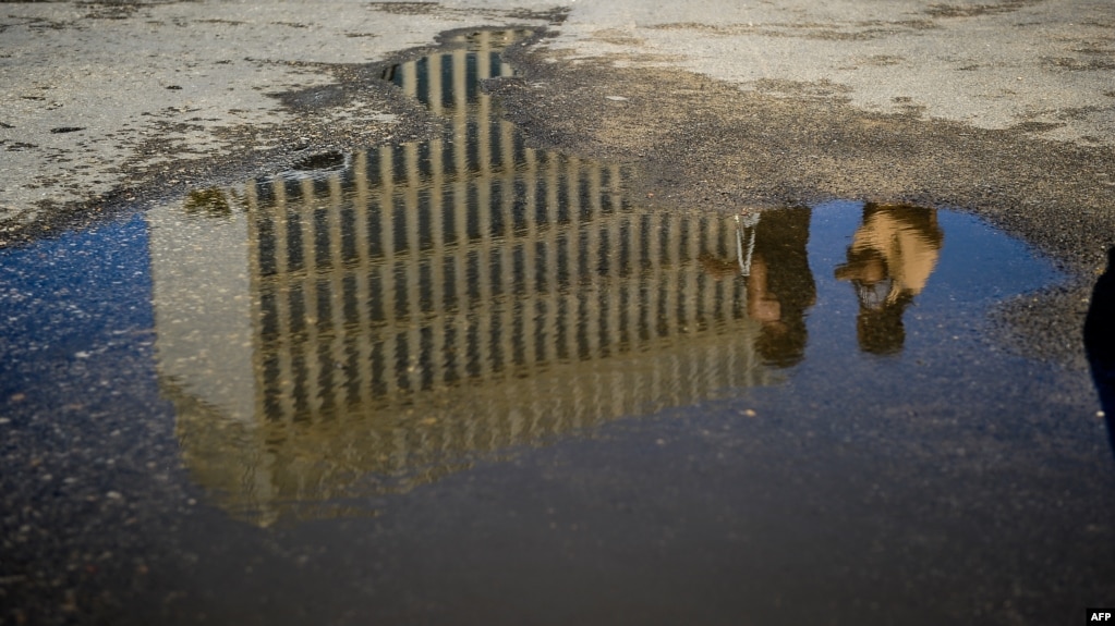La embajada de EEUU en La Habana reflejada en un charco de agua.