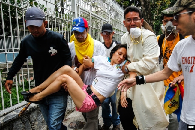 Un grupo de hombres carga a una mujer desmayada a causa de los gases lacrimógenos durante una confrontación de opositores con la Policía Nacional Bolivariana en Caracas.