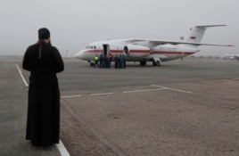 Sacerdote ortodoxo recibe al avión del Ministerio de Situaciones de Emergencia en San Petersburgo.